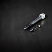 Two wireless microphones on a dark wooden surface