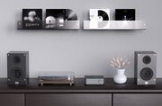 Audio equipment including speakers and a turntable on a shelf with a minimalistic design.