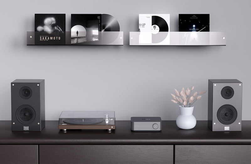 Audio equipment including speakers and a turntable on a shelf with a minimalistic design.