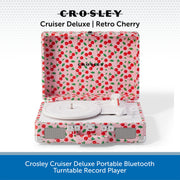 Crosley Cruiser Deluxe portable Bluetooth turntable record player in cherry print, shown open with the record platter and controls visible against a white background with a blue text banner at the bottom.