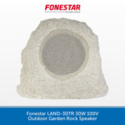 A rock-style outdoor garden speaker by Fonestar, shown from the front on a white background with a blue text banner at the bottom. The speaker has a rough, natural stone texture in light gray and beige tones, with a circular mesh-covered speaker grille in the center.