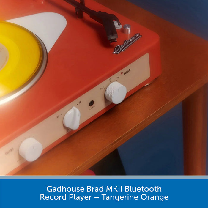 Gadhouse Brad MKII Bluetooth record player in tangerine orange on a wooden surface.