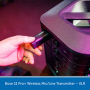 Hand plugging a wireless mic transmitter into a piece of audio equipment with Bose S1 Pro+ branding.