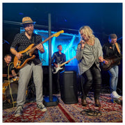 Band performing on stage with a blue curtain and rug