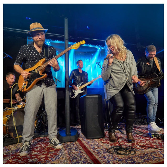 Band performing on stage with a blue curtain and rug