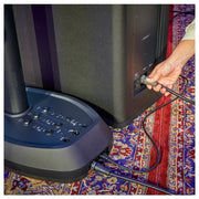 Person plugging a cable into a speaker on a patterned rug